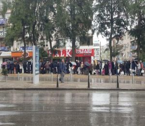 Buca'da yağmur altında askıda ekmek kuyruğu